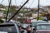 Downed utility poles on Smith Bay Road in Charlotte Amalie with card driving under it 