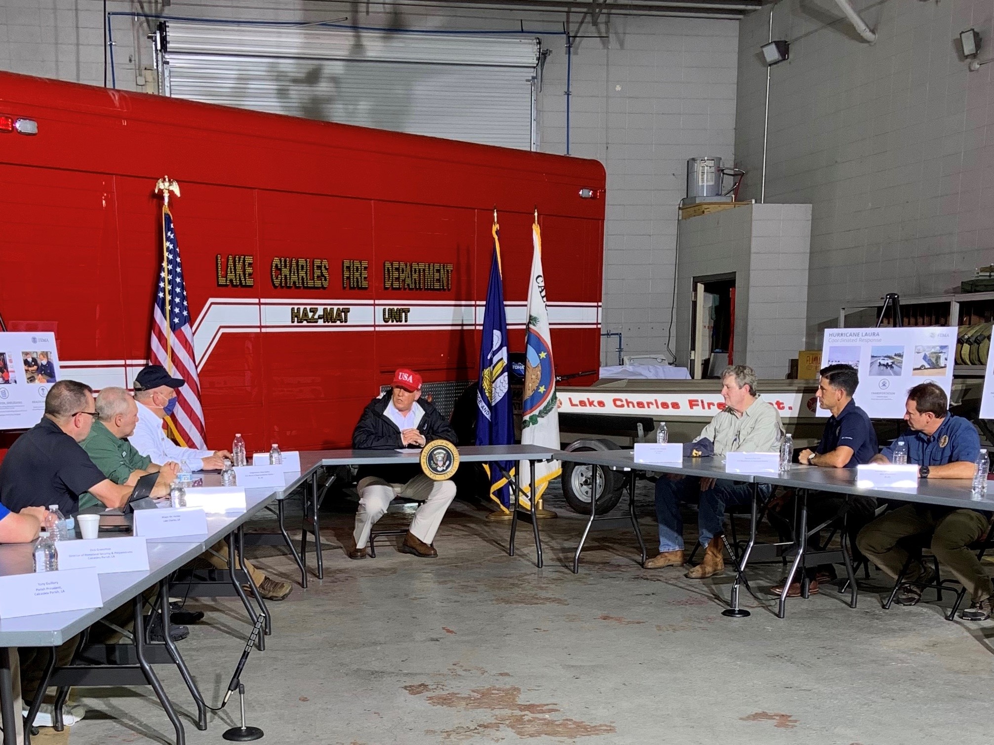 Government officials sitting at two long tables inside a fire station