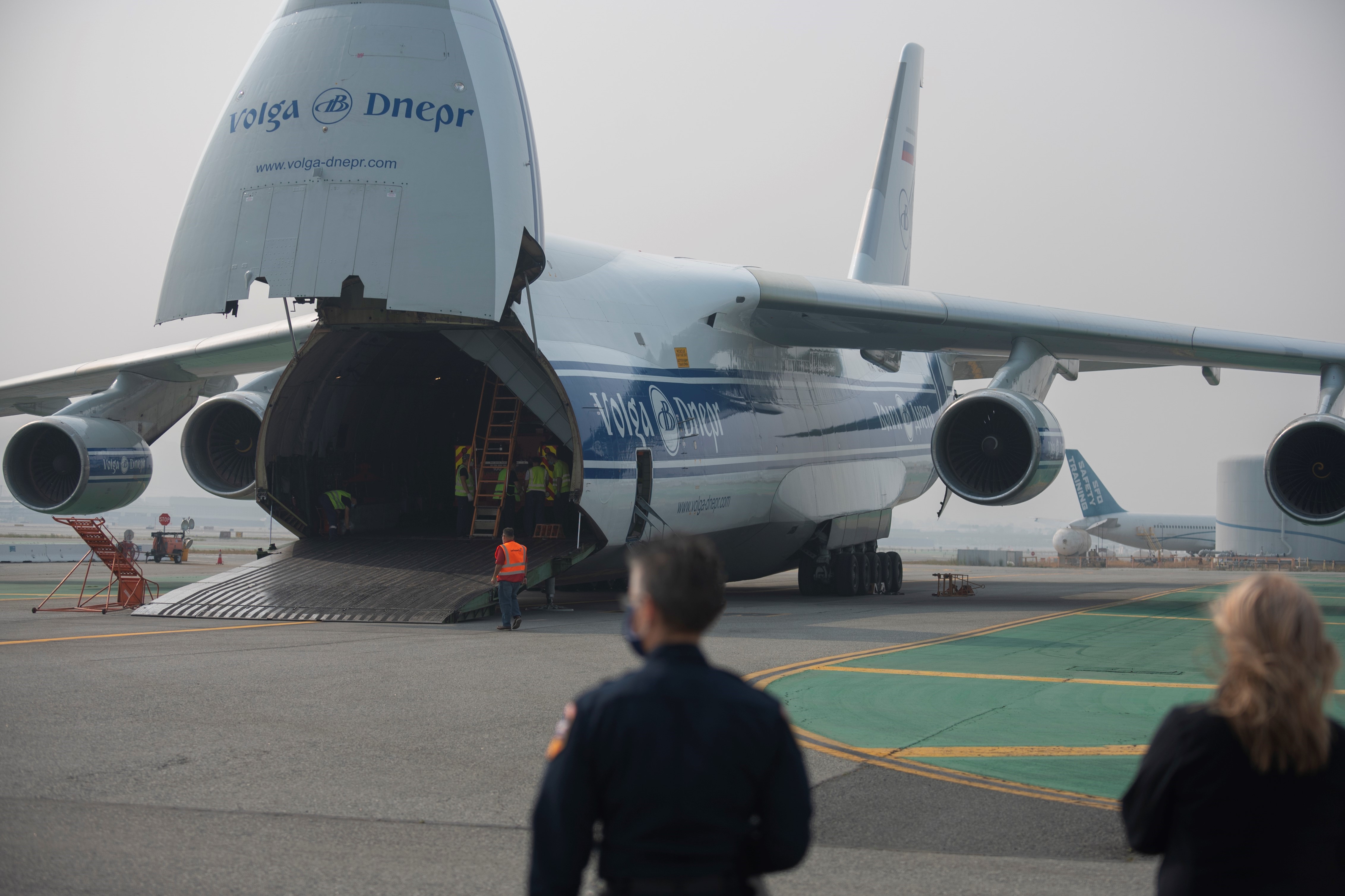 the back of an airplane open and a man and a women at the bottom right of the photo