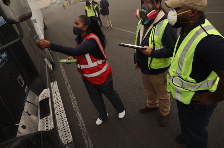 2 mean and 1 women standing on the side of a 18 wheeler truck