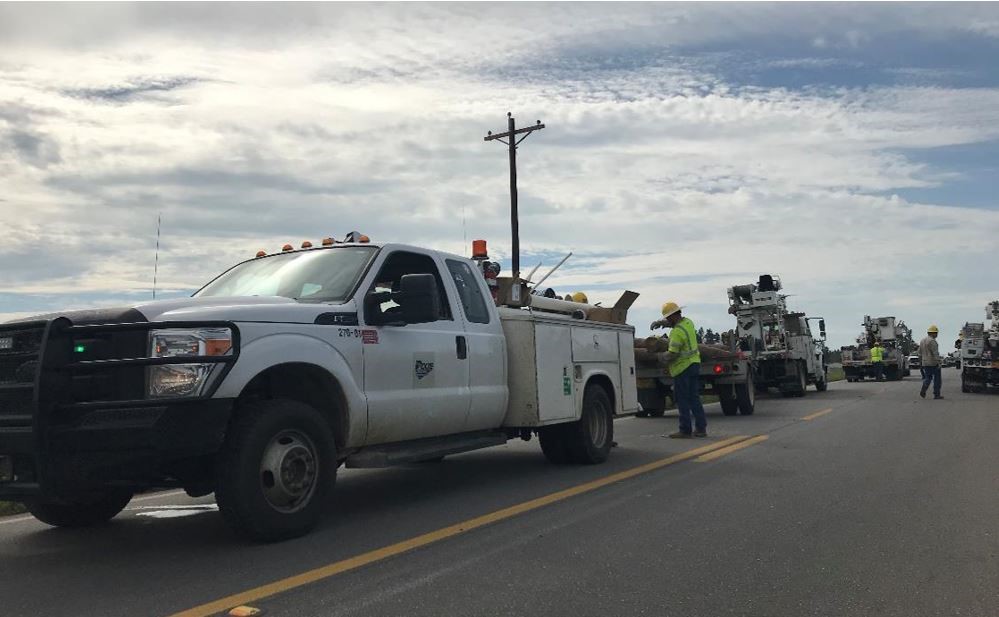 line crew utility trucks work delivering replacement power poles to restore power in alabama 