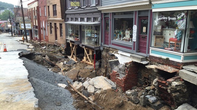 A collapsed road in front of historic multi-colored storefront shops.
