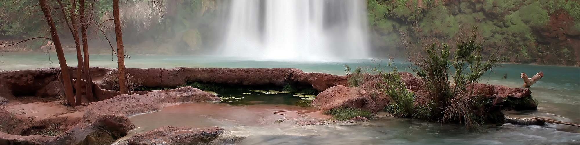 Photo of waterfall behind red rock landscape in Havasupai Gardens, Arizona