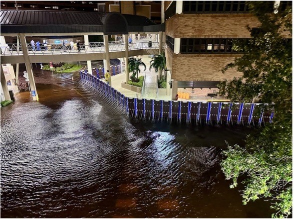 A portable flood barrier system is deployed in an arc formation, successfully preventing floodwaters from entering the building.