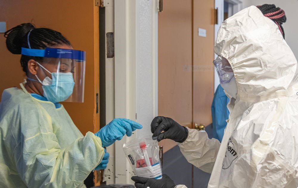 A female nurse pulling out a tube out of a zip lock page from another medical professional