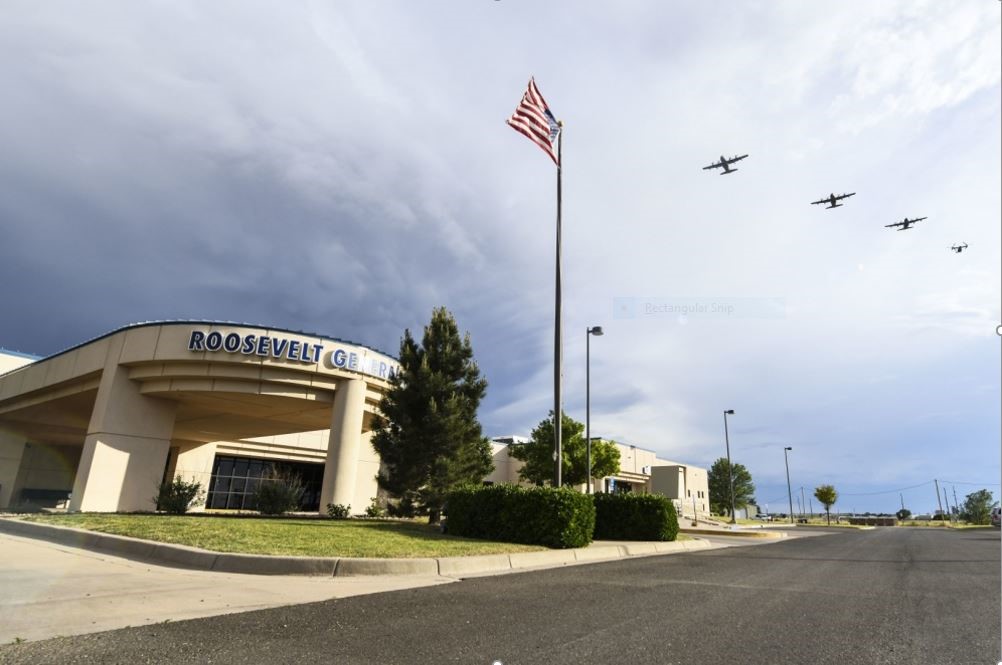 A building with an American Flag in front of it and 4 airplanes flying by