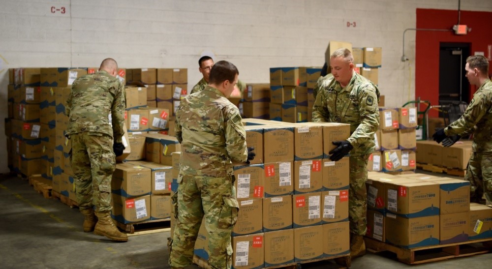 5 male soldiers stacking boxes of ppe