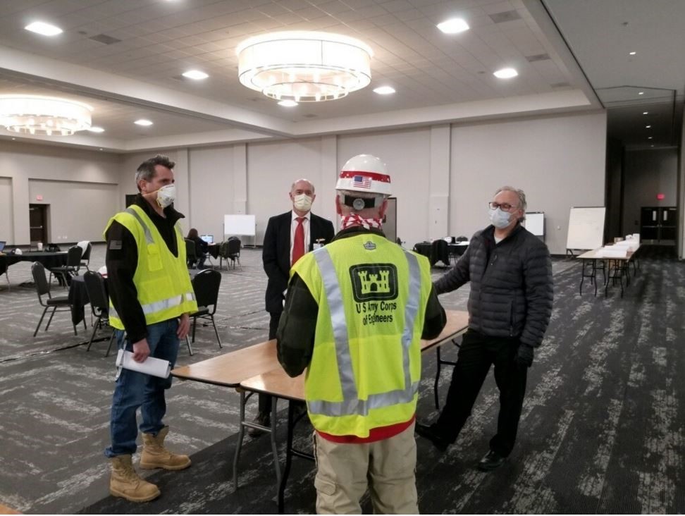 four men standing around the table talking