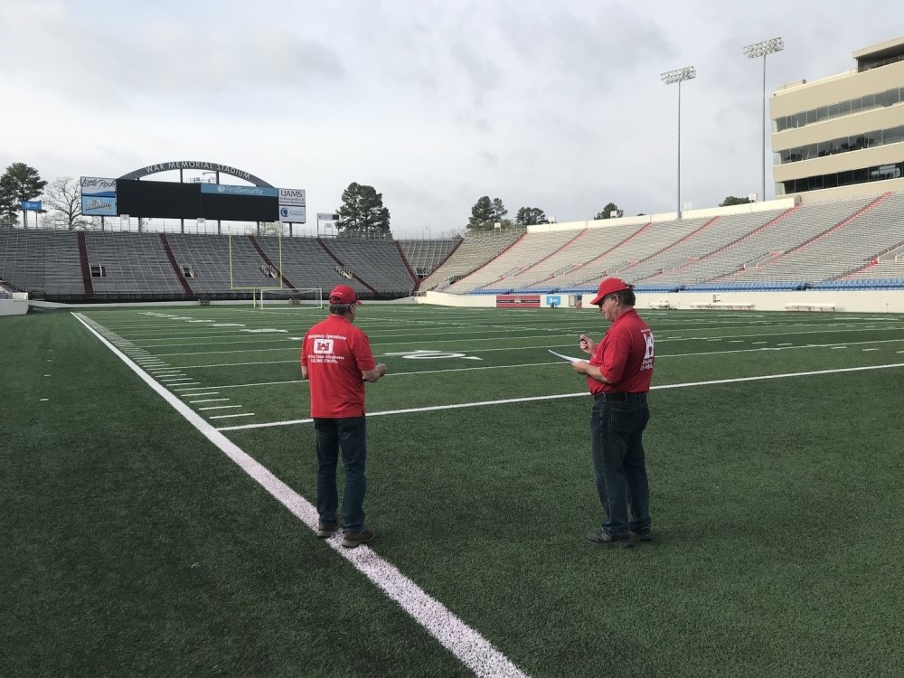 Two men standing on the side line of a football stadium