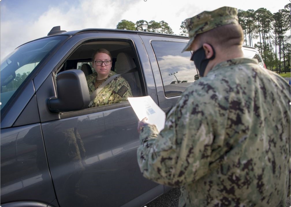 A male soldier standing on the driver side of a suv with a female soldier inside of the vehicle