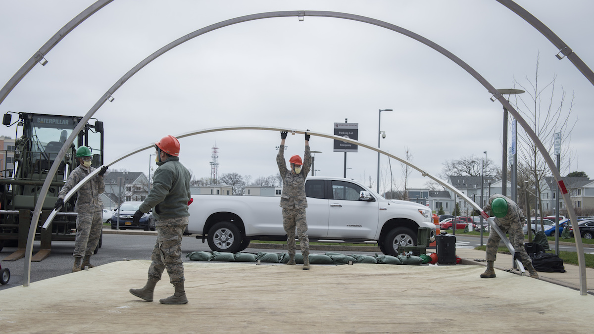 Air National Guardsmen support beams for a tent.