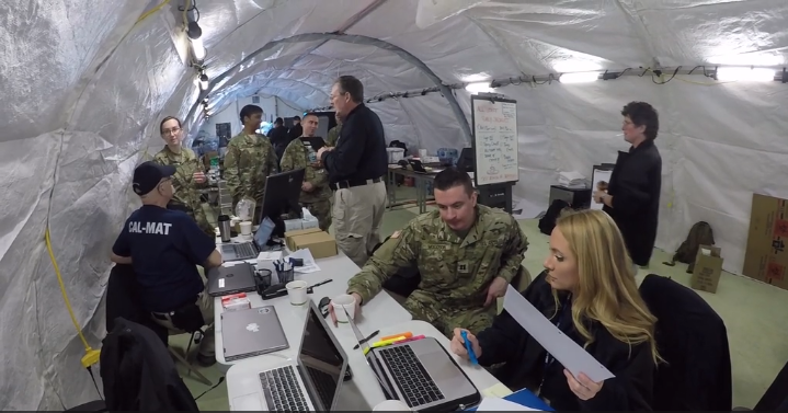 A female on her laptop with a male soldier looking at it