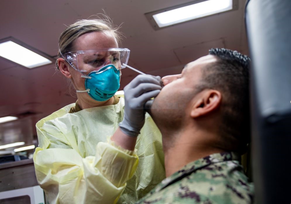 A female nurse testing a male soldier for COVID-19