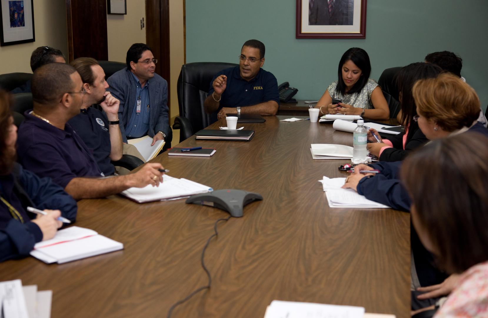 FEMA employees in blue polo shirts sitting around a conference table