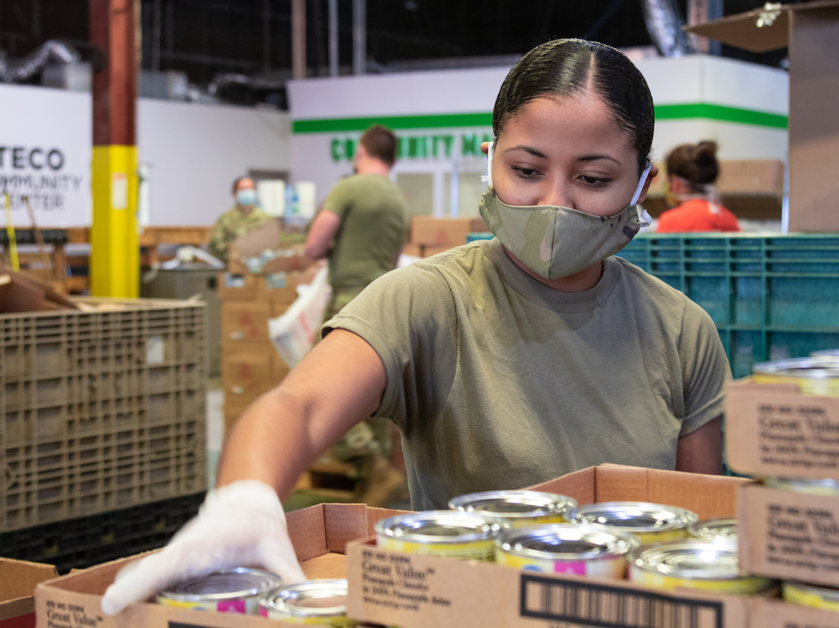 A soldier puts cans of foods into boxes.