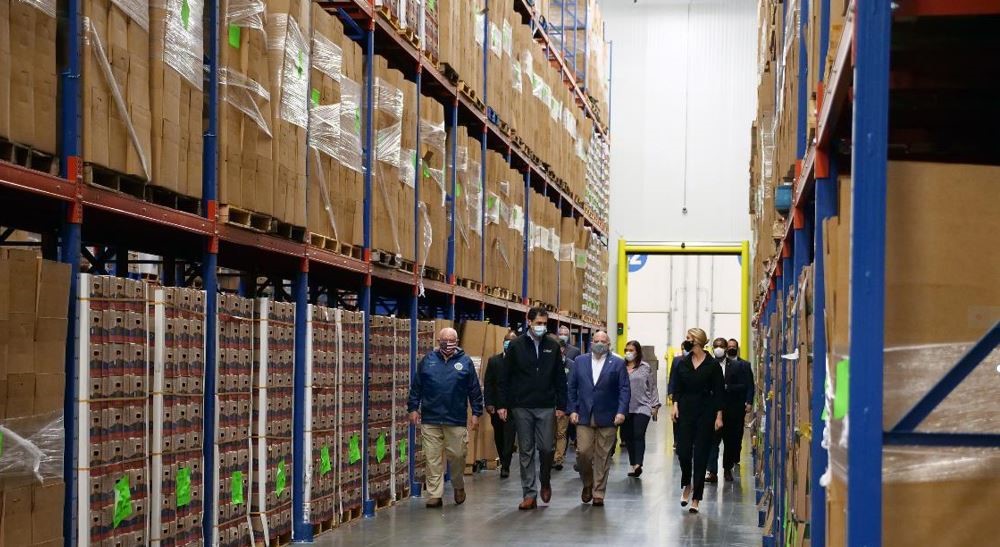 A group of a 11 people both men and women walking through a warehouse