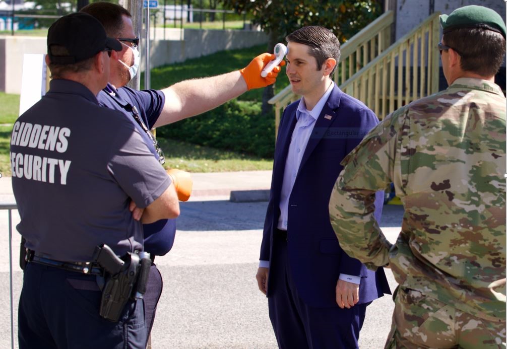 4 men standing around and one man is checking the temperature  of Florida House of Representative