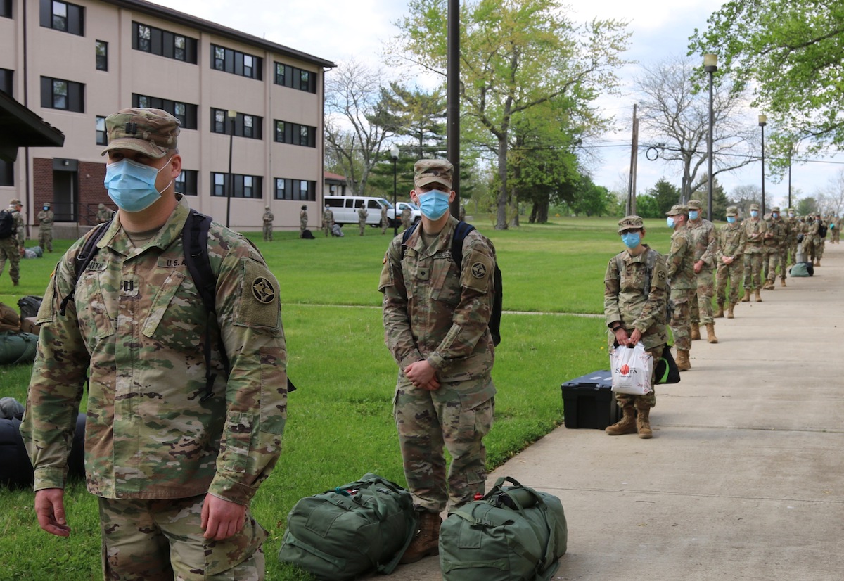 Military personnel stand in line distanced six feet apart.