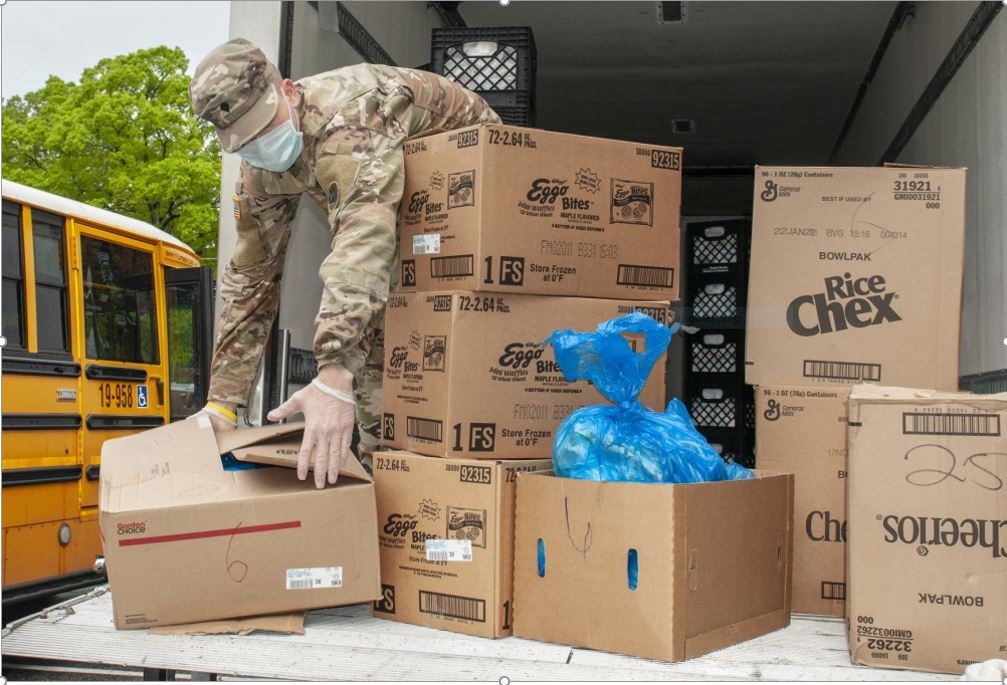 A male soldier moving boxes on the back of a truck