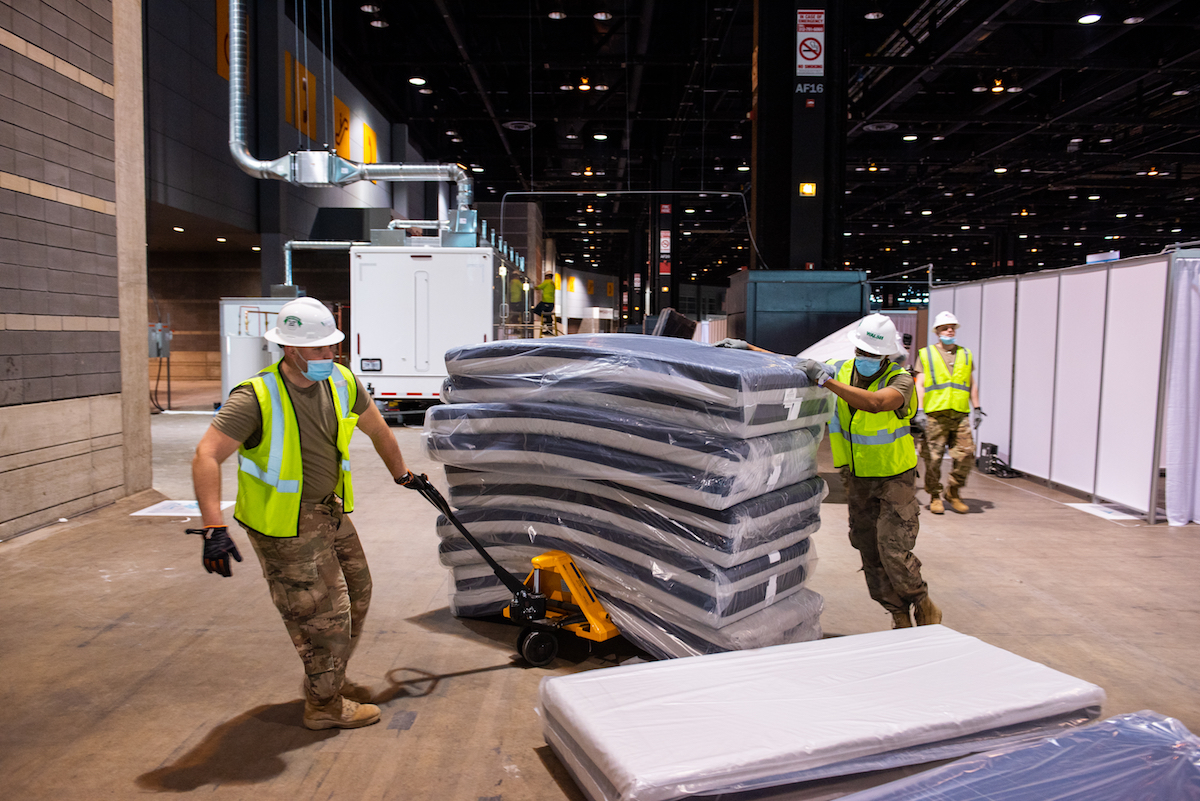 Soldiers use a pallet truck to move hospital mattresses in the convention center.