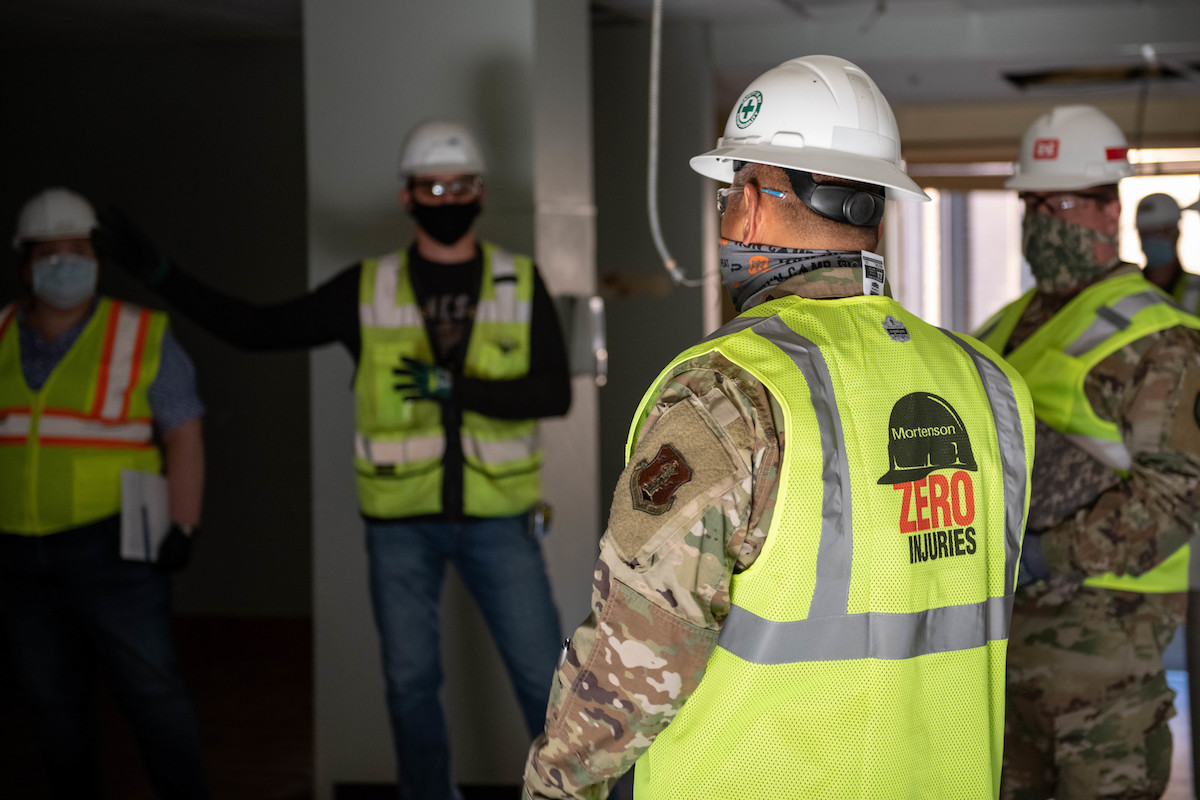 Soldiers and construction workers inspect a facility.