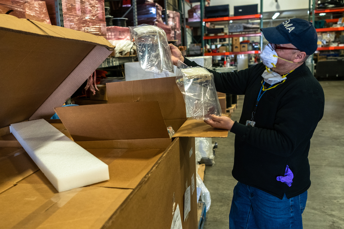 Man looks inside box and lifts out medical face masks. 