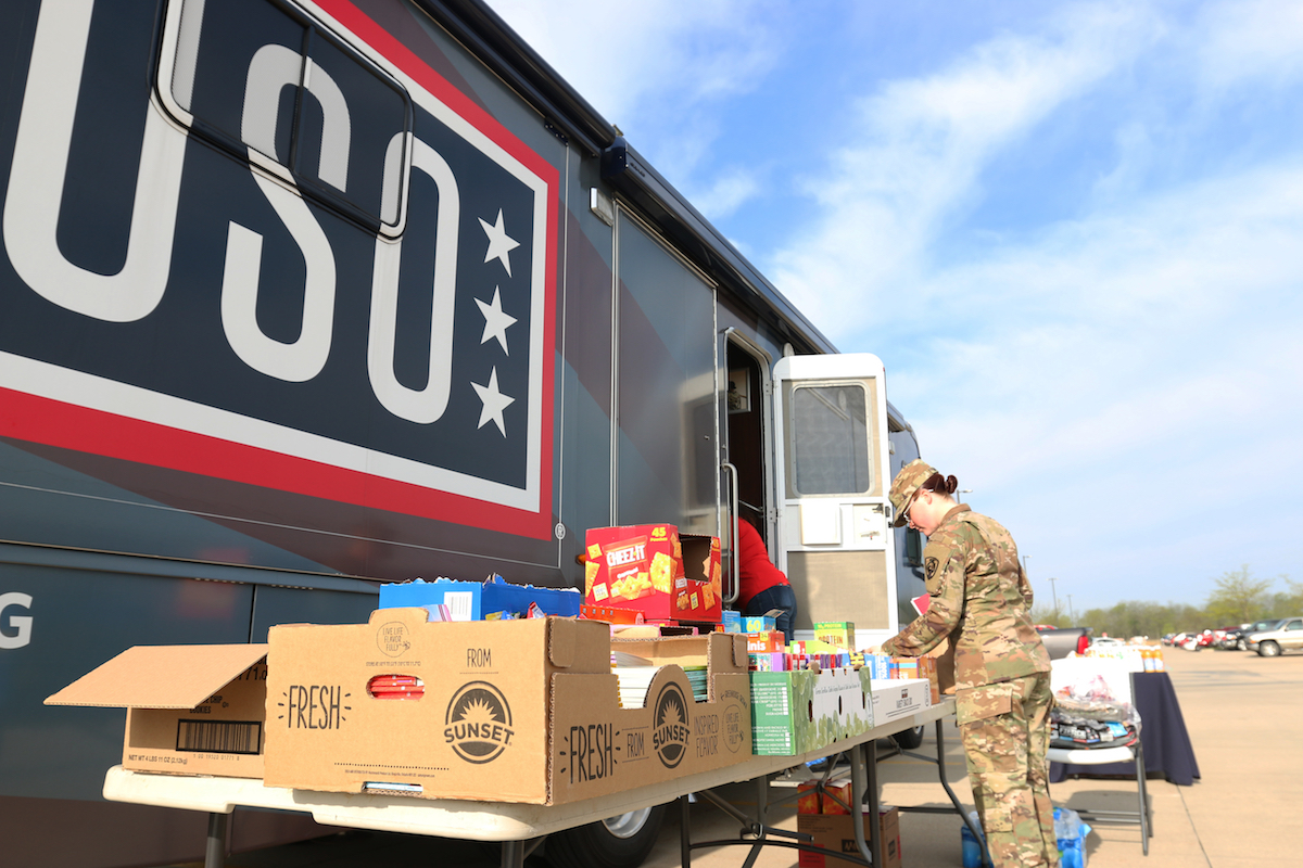 Woman service member gets food at a USO table.