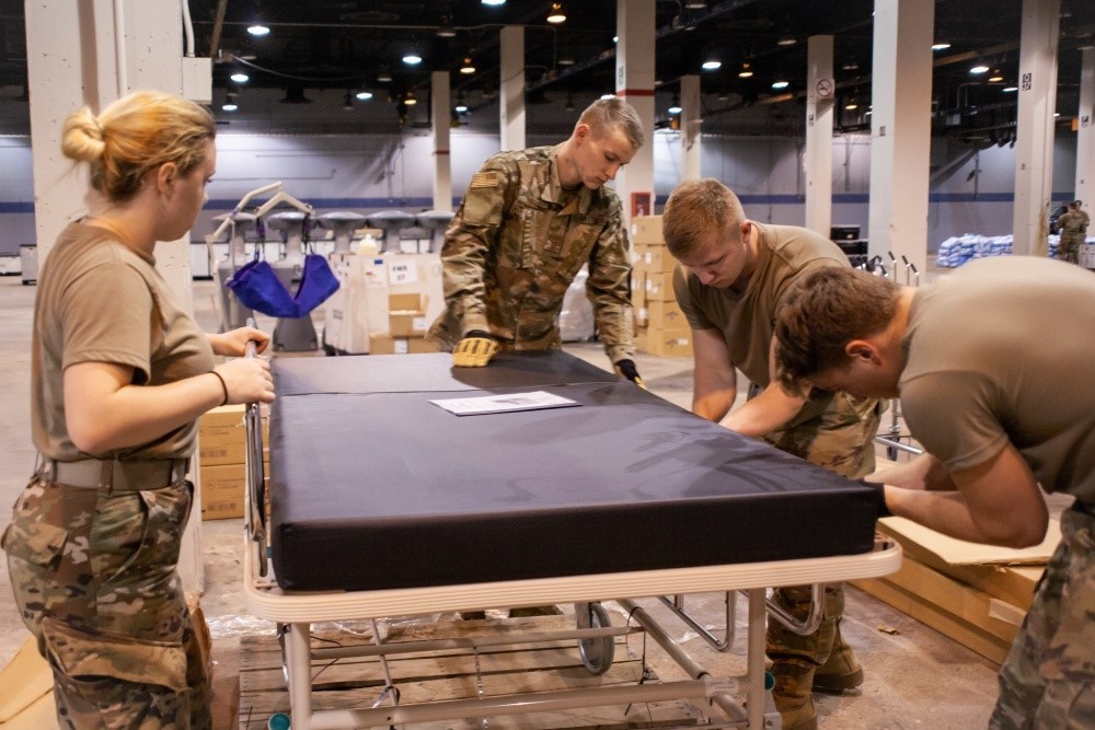 3 male soldiers and one female soldiers putting together a medical bed