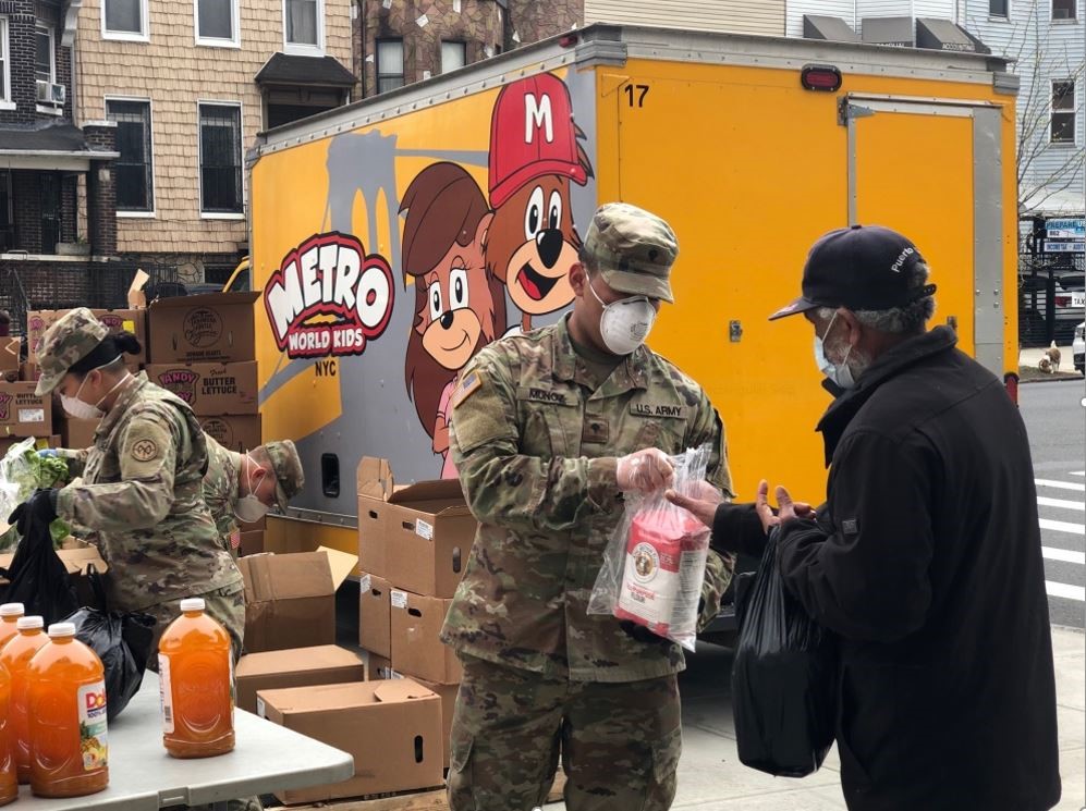 2 male soldiers and one female soldier bagging up food to give out to people