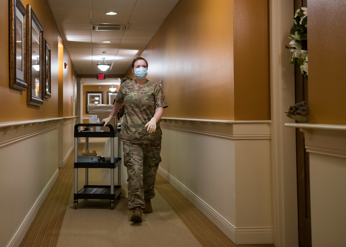 Woman walking down hallway pulling a trolley.