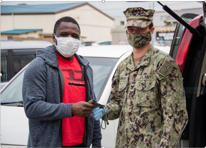 A male solider given a mask to a civilian male