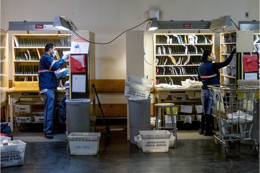 A male postman putting mail on the shelves and female postwoman putting mail o the shelves