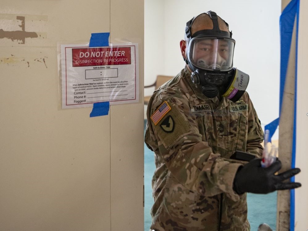 male soldier with a face mask is working through a door