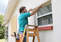 Man  measuring each window to  secure the shutters