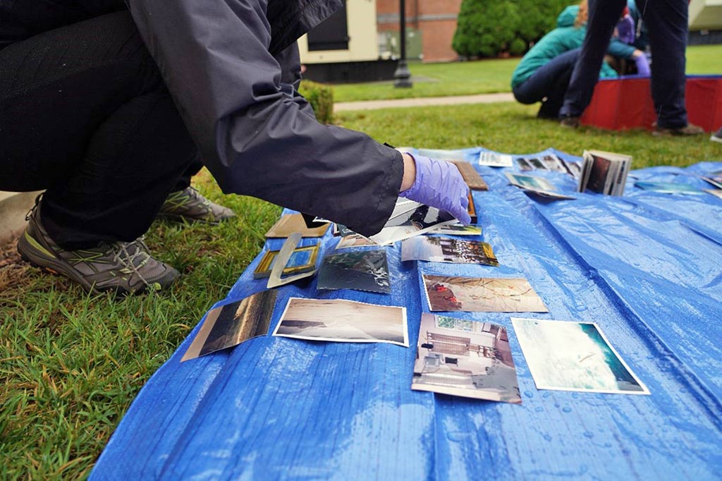 Person puts photographs onto blue tarp