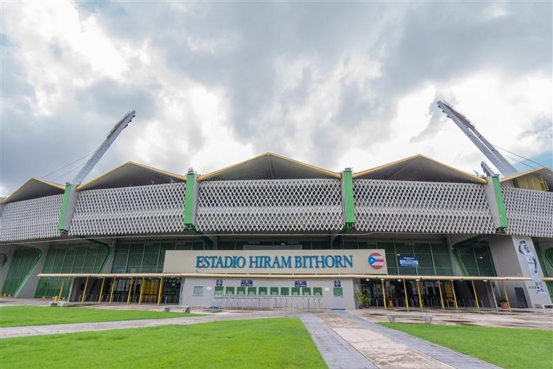 Stadium front view, white building with green accents.