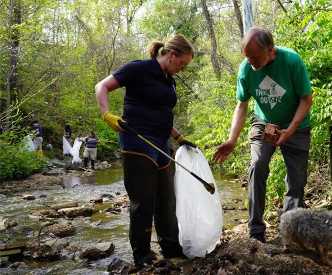 FEMA Administrator Deanne Criswell (left) and Washington Parks & People Executive Director and President Steve Coleman remove trash from Watts Branch Stream during an Earth Day service project at Marvin Gaye Park April 22.