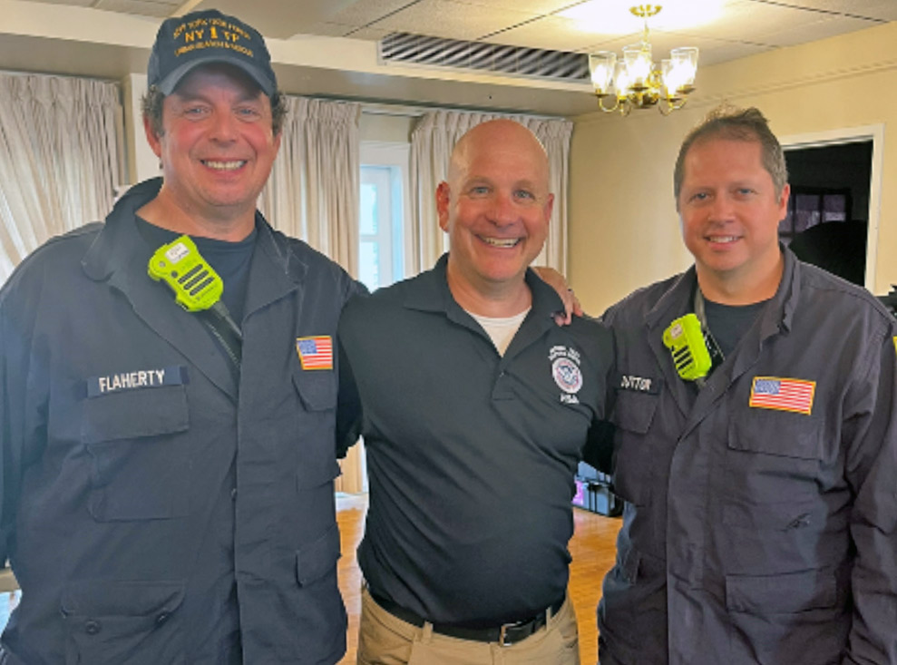 Three men smile and pose for camera.