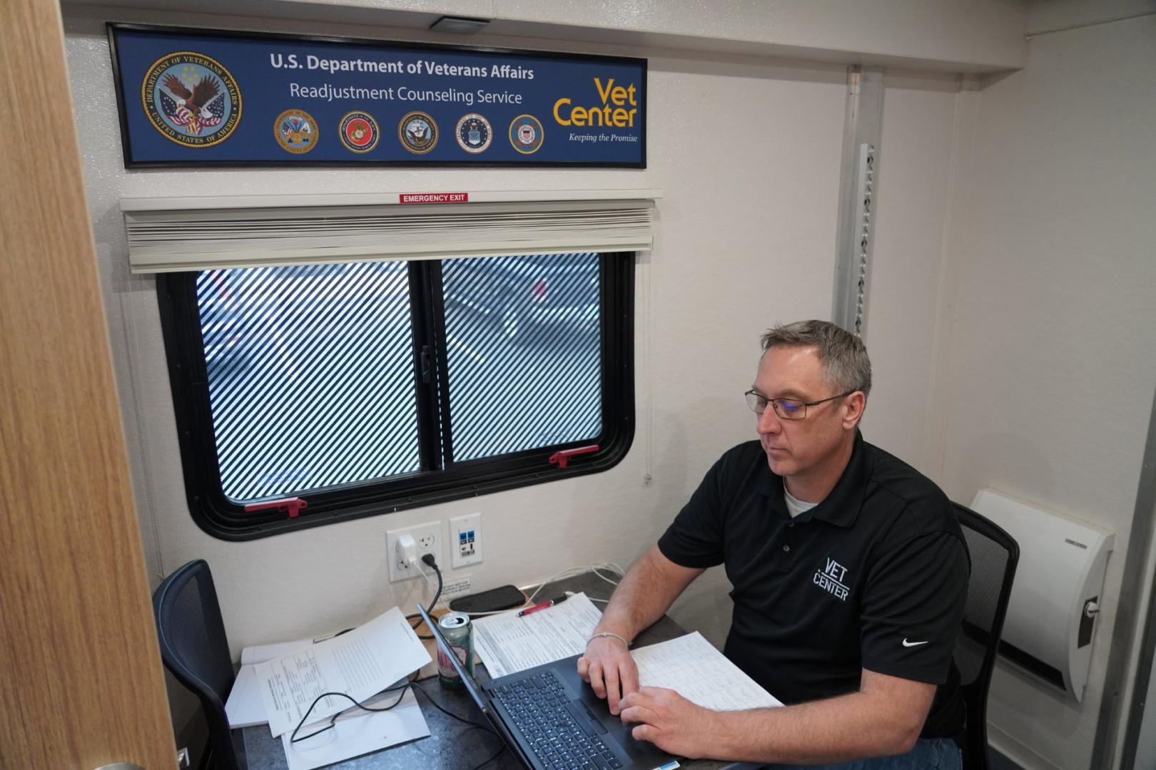 A person sitting at a table inside typing on their computer.