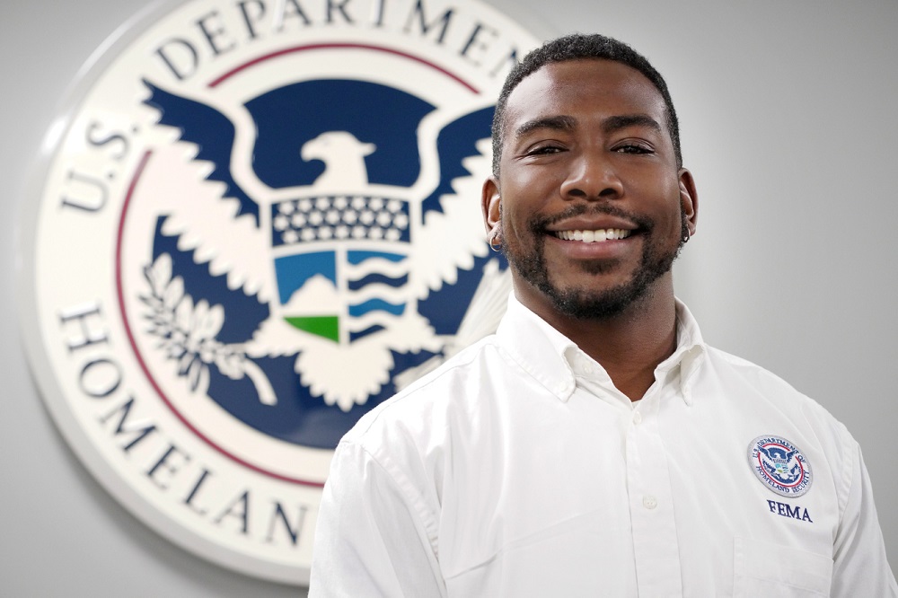 Smiling man standing in front of FEMA seal.
