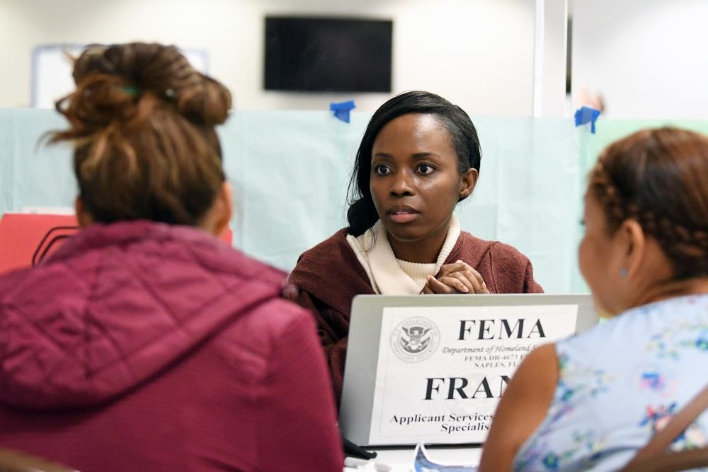 Two women talking to a FEMA specialist at her laptop