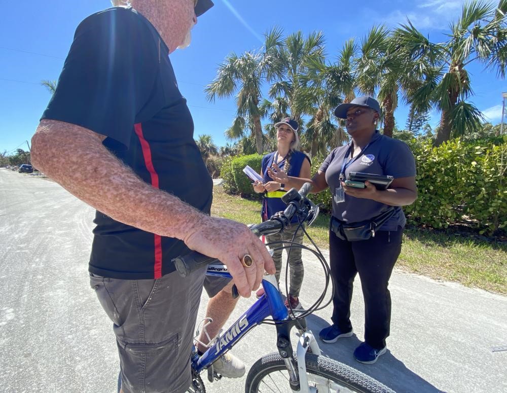 Two women and man with a bike in front of him talking 