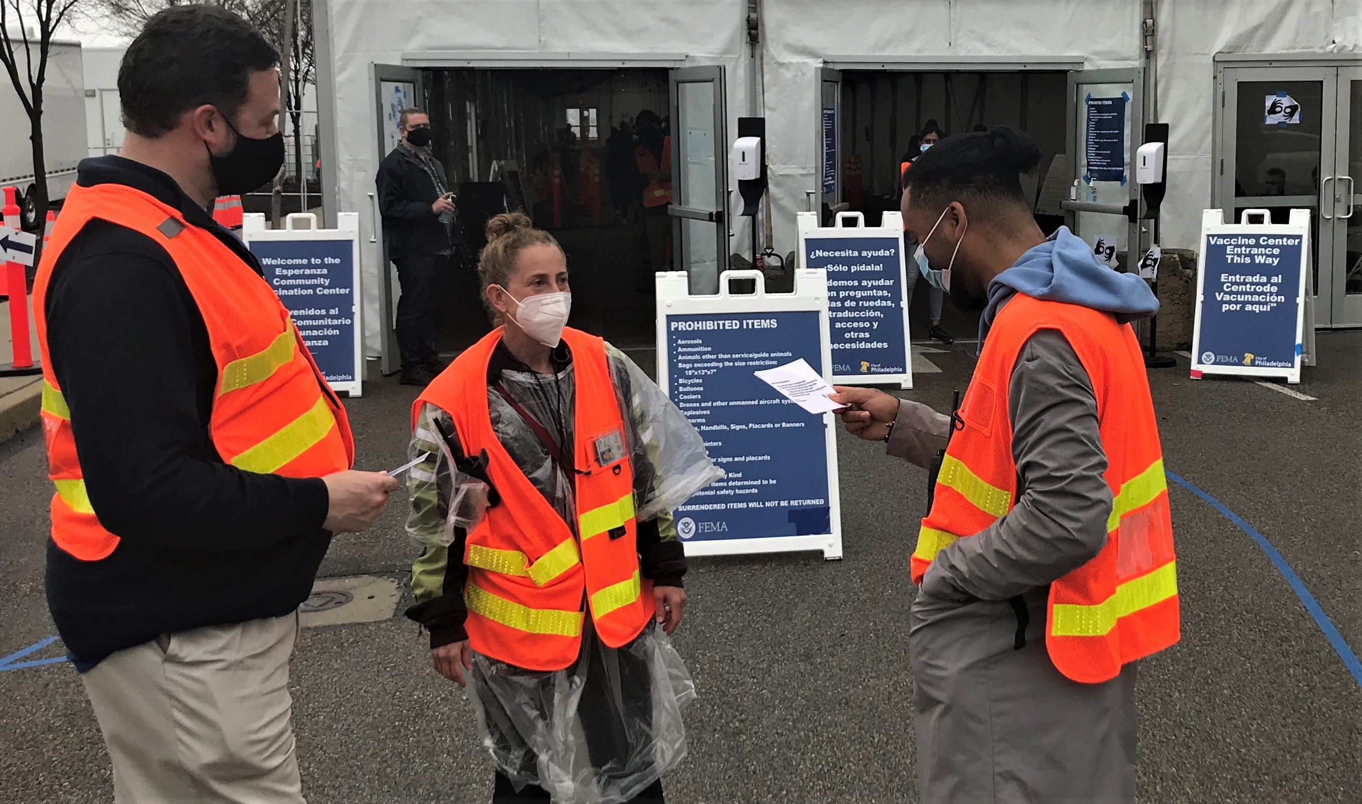 Staff at Esperanza Community Vaccination Center stand outside the clinic where signage in multiple languages is posted for patients who speak languages other than English. 