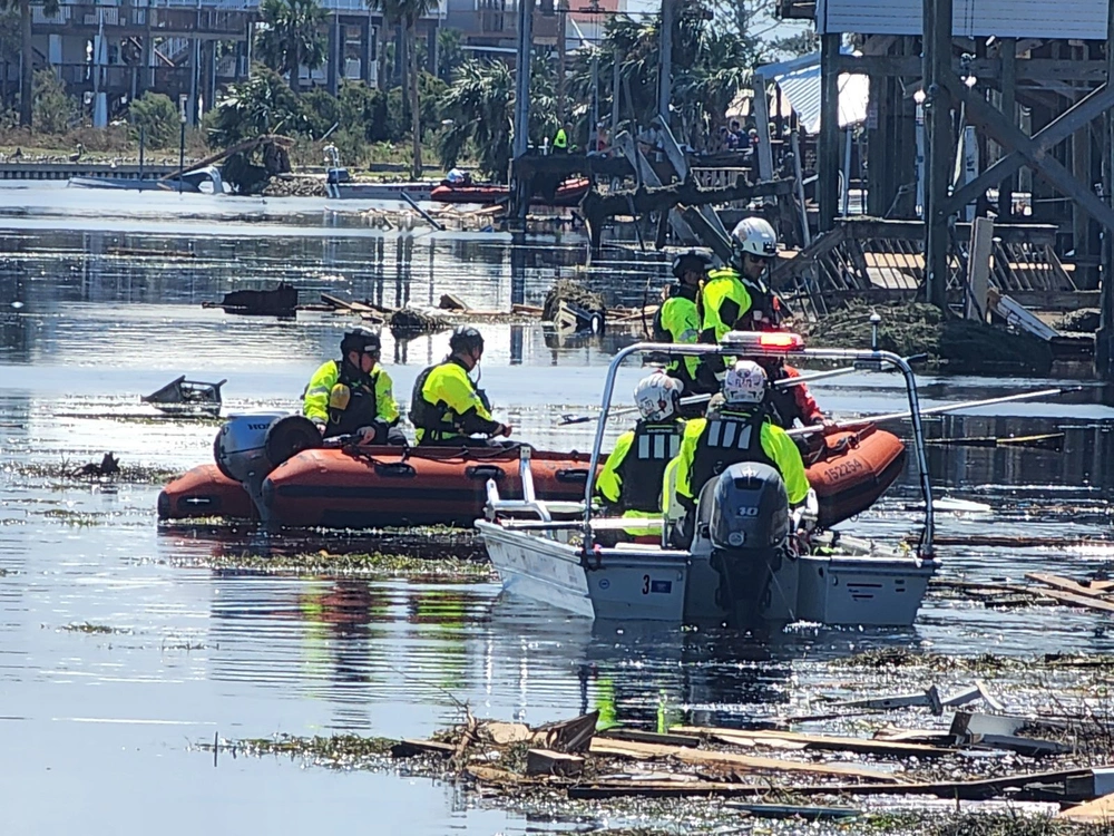 coast guard riding in boats through flood waters