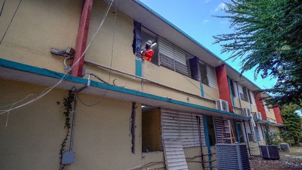 men fixing windows of a yellow school building 