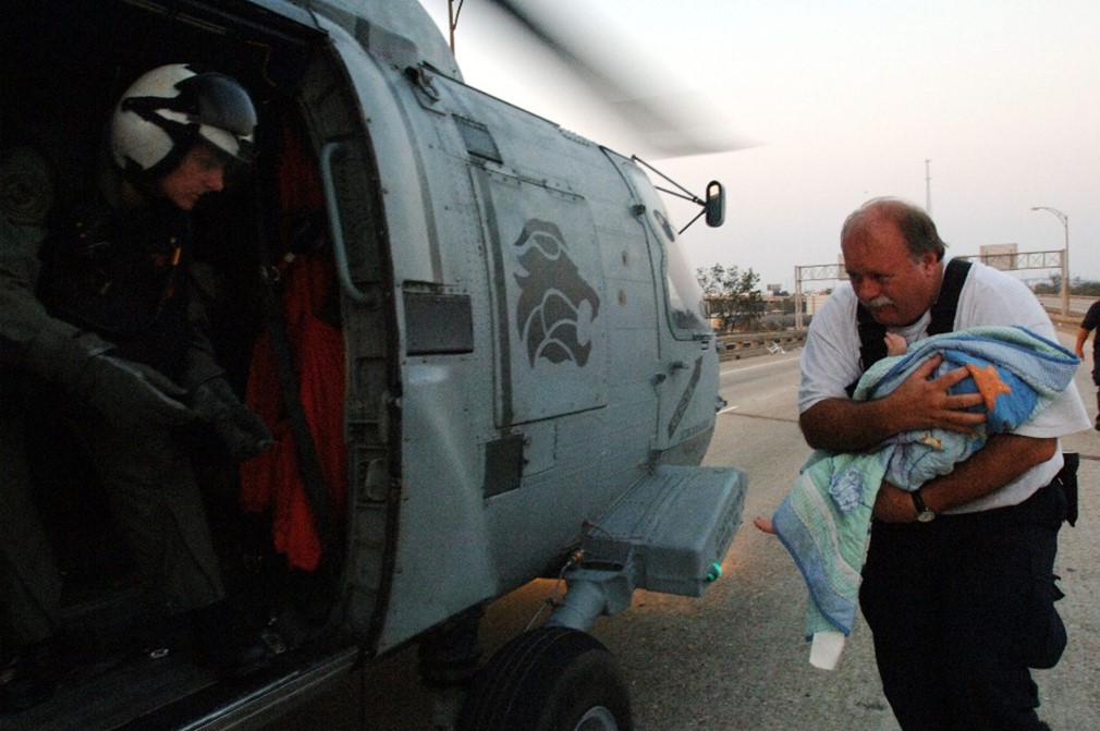 A man carrying a baby on to a military helicopter.