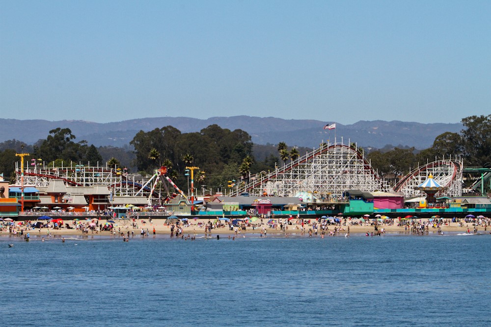 City of Santa Cruz, California shoreline. People on the beach, a view of rollercoaster behind the beach.