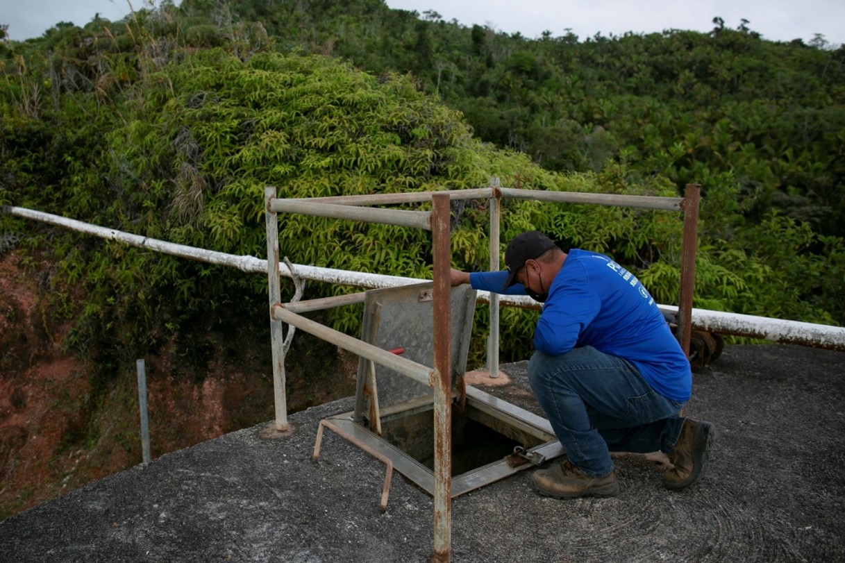 Man with blue shirt looking down small door