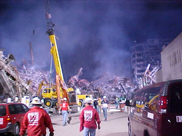 Workers in red jackets in front of a yellow crane at Ground Zero
