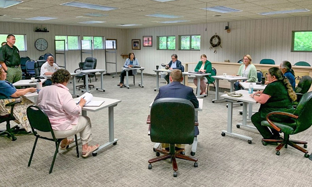People in a classroom sitting in desks facing each other in a circle.